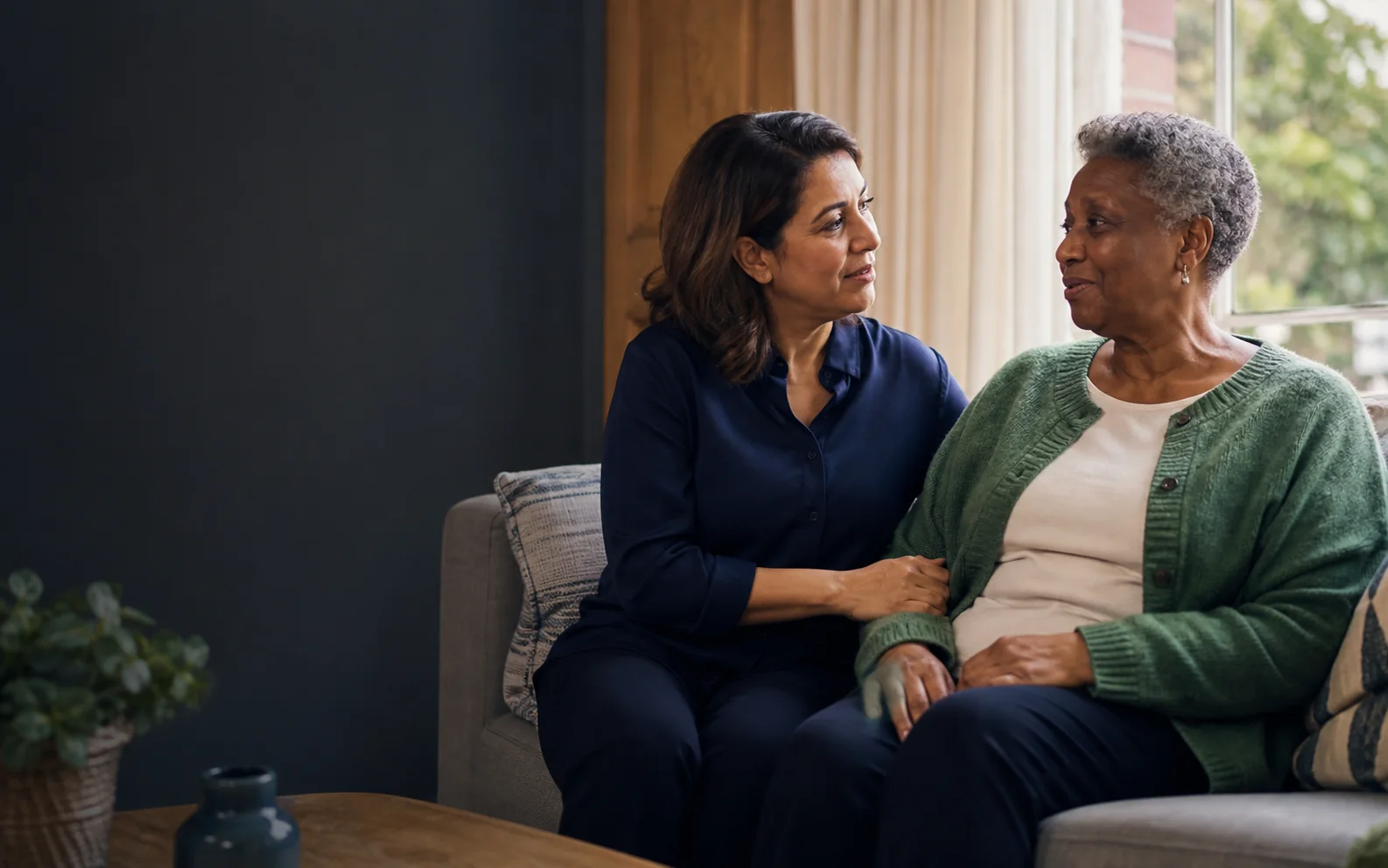 A care professional sharing a warm conversation with an older woman at home